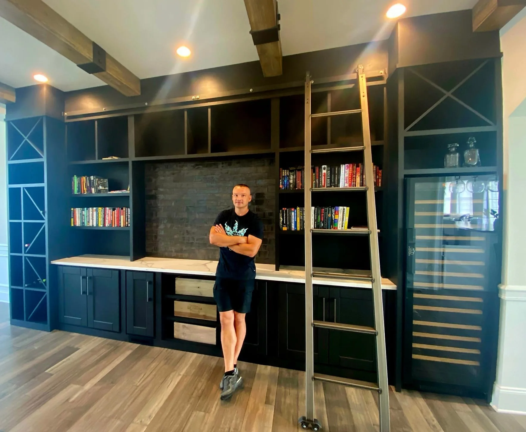 Rafal standing beside a floor-to-ceiling navy library with a rolling ladder